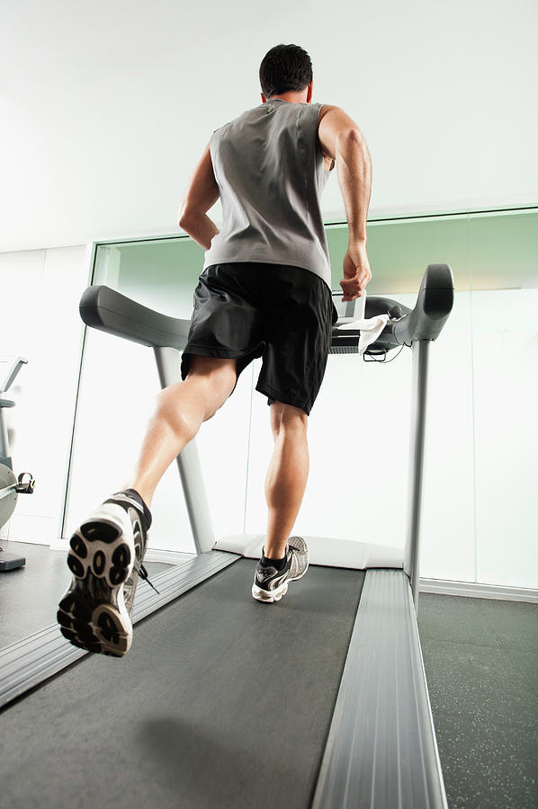 Mixed Race Man Running On Treadmill Photograph by Erik Isakson