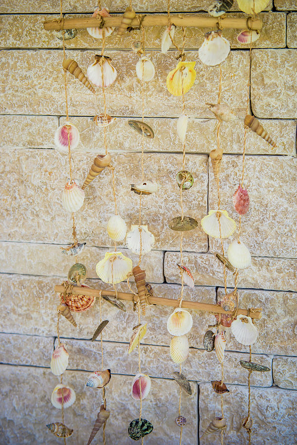 Mobile Made Of Shells In Front Of Stone Wall Photograph by Bildhbsch