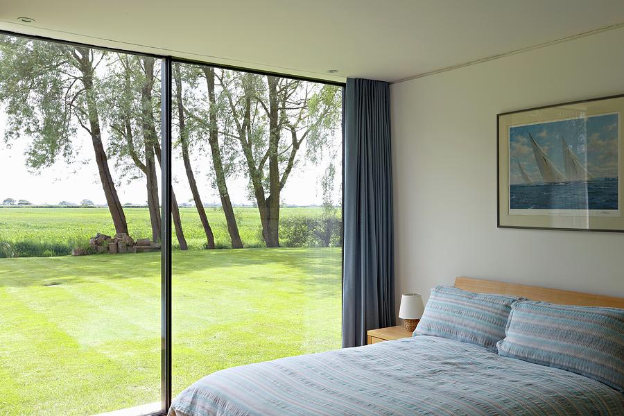 Modern Bedroom With Glass Wall Overlooking Sunny Lawn Photograph by