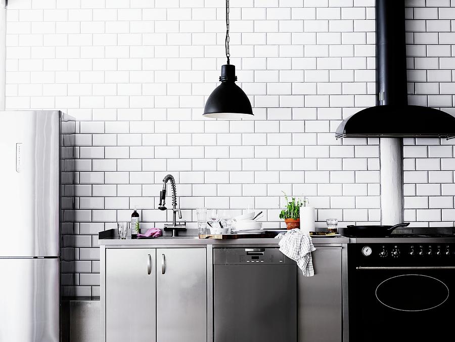 Modern Kitchen Counter In Stainless Steel And Black Against White-tiled Wall Photograph by Mikkel Adsbl