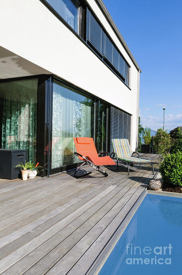 Modern white family home with wooden deck and  small pool right at the livingroom windows. Photograph by Ulrich Wende