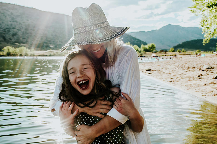 Mom And Daughter Hugging And Laughing While Standing In A Lake