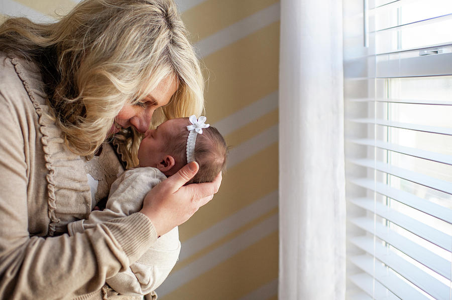 Colorado Springs Photograph - Mother Happily Holding Newborn Daughter Up To Face At Home by Cavan Images