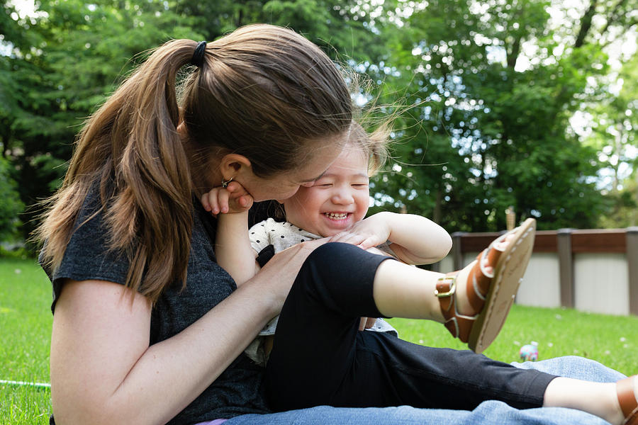 Parenthood Movie Photograph - Mother Hugs Happy Laughing Toddler Daughter While Sitting Outdoors by Cavan Images