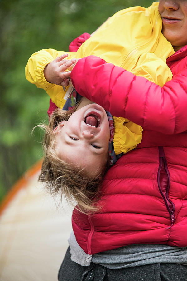 Mother Playfully Tickles Daughter While Holding Her Upside Down