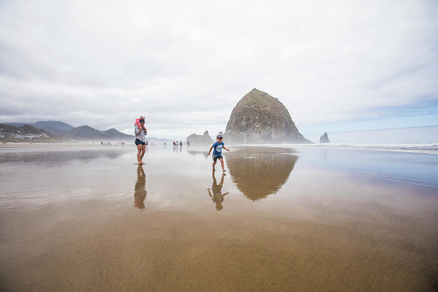 Nature Photograph - Mother Watches As Son Runs Along Wet Sand Beach Near Haystack Rock. by Cavan Images