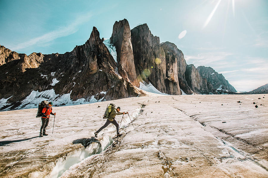 Summer Photograph - Mounatineer Crosses A Glacial Crevasse On A Sunny Day, Baffin Island. by Cavan Images
