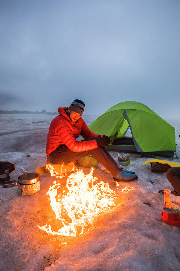Mountain Photograph - Mountaineer Enjoys Campfire While Camping On A Glacier, Baffin Island by Cavan Images