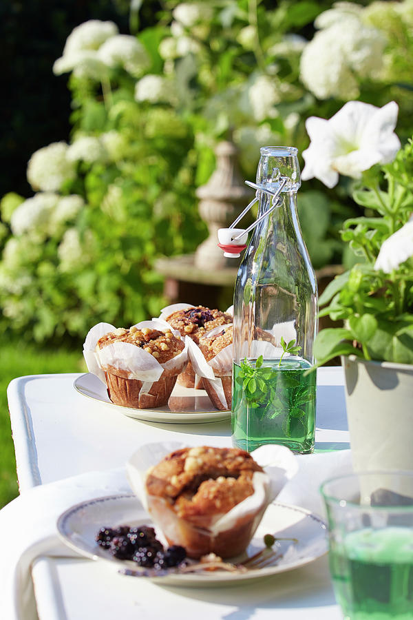 Muffins And Swing-top Bottle Of Mint Syrup On Garden Table Photograph by Sven C. Raben