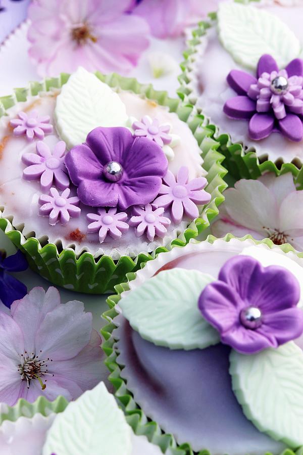 Muffins Decorated With Glac Icing And Purple Sugar Flowers Photograph by Angelica Linnhoff