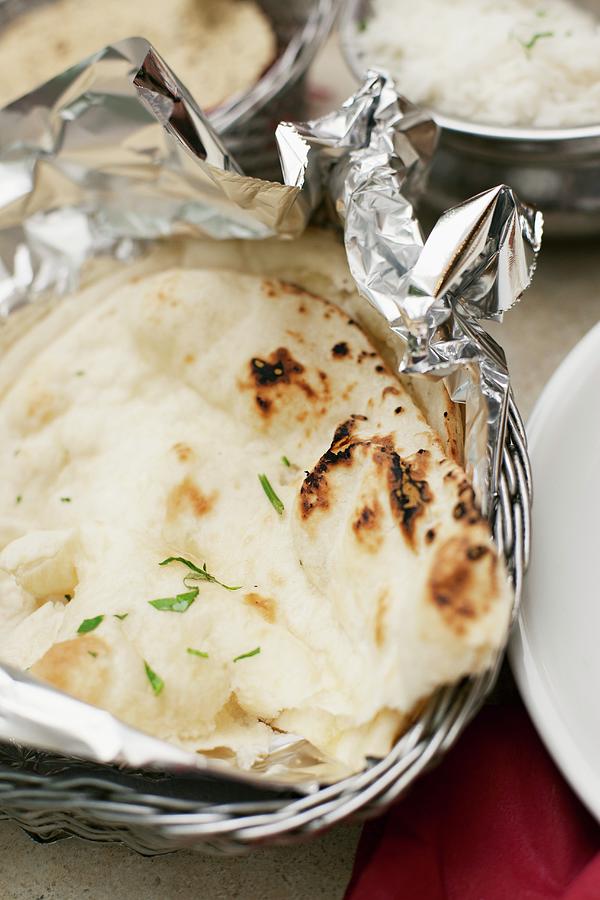 Naan Bread In Tin Foil In A Breadbasket Photograph by Alex Hinchcliffe