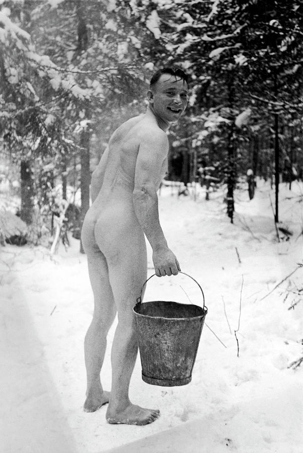 Bucket Photograph - Naked Finnish soldier carrying a bucket of water back to his friends who are enjoying a sauna bath nearby. by Carl Mydans