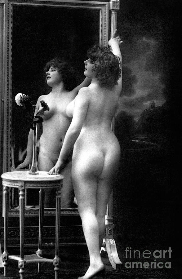 Naked woman posing in front of a mirror near a pedestal table, 1913 Photograph by French School