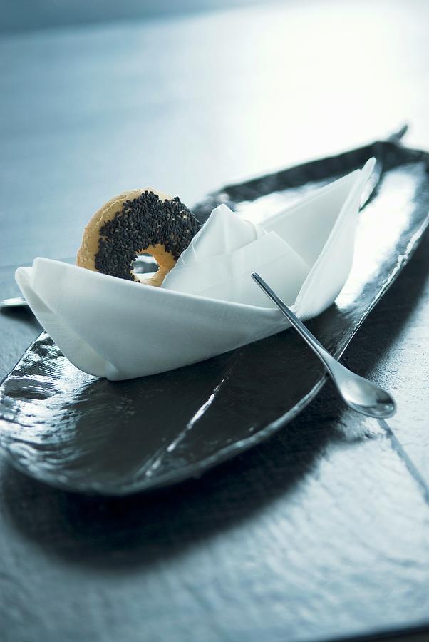 Napkin Boat With Spoon As Rudder And Round Biscuit As Decorative Place Setting On Long, Narrow Plate Photograph by Matteo Manduzio
