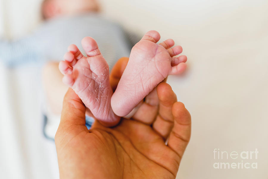 Newborn feet skinning held by mommy Photograph by Joaquin Corbalan