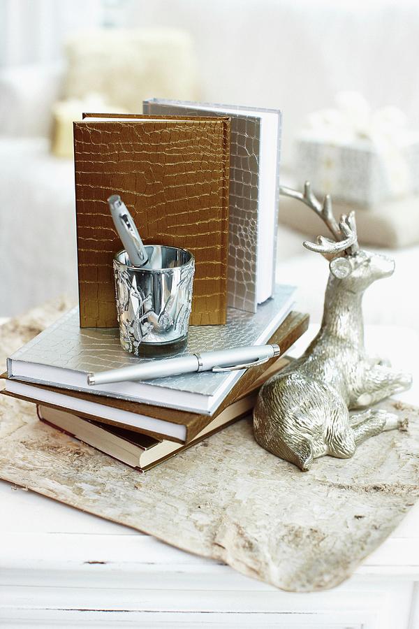 Note Books With Gold And Silver Mock-croc Bindings Next To Silver Reindeer Ornament And Writing Utensils On Vintage Paper Photograph by Biglife