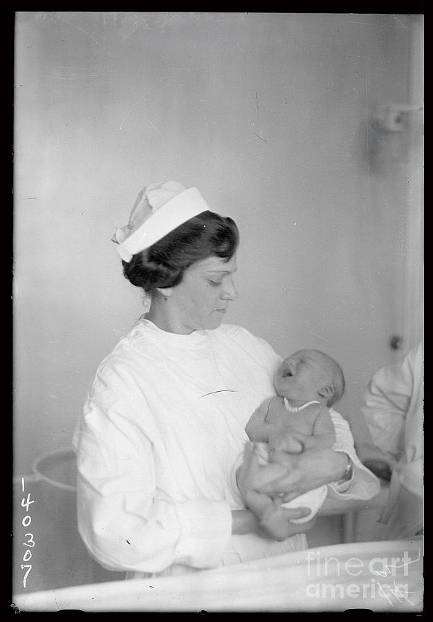 Nurse Holding Baby With Identifying Photograph by Bettmann