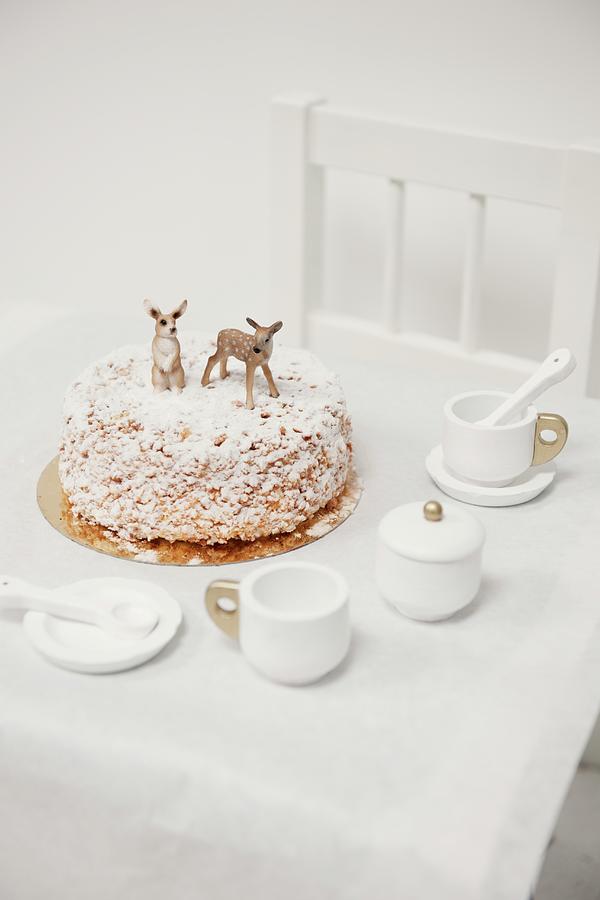 Nut Cake Decorated With Icing Sugar And Animal Figurines On Childs Table With Dolls Tea Set Photograph by James Stokes