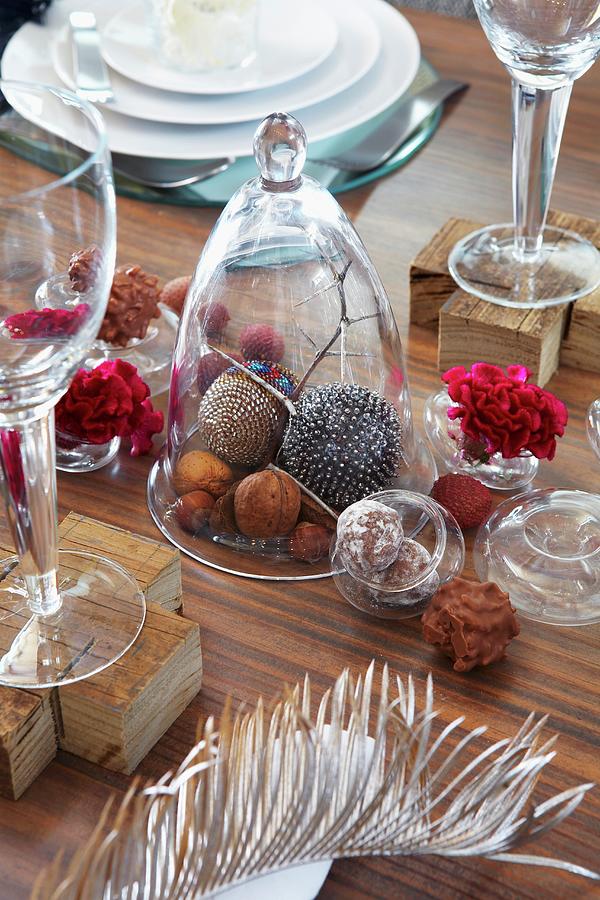 Nuts And Decorative Baubles Under A Glass Cloche And Pralines, Flowers And A Feather On A Table Decorated For Christmas Photograph by Great Stock!