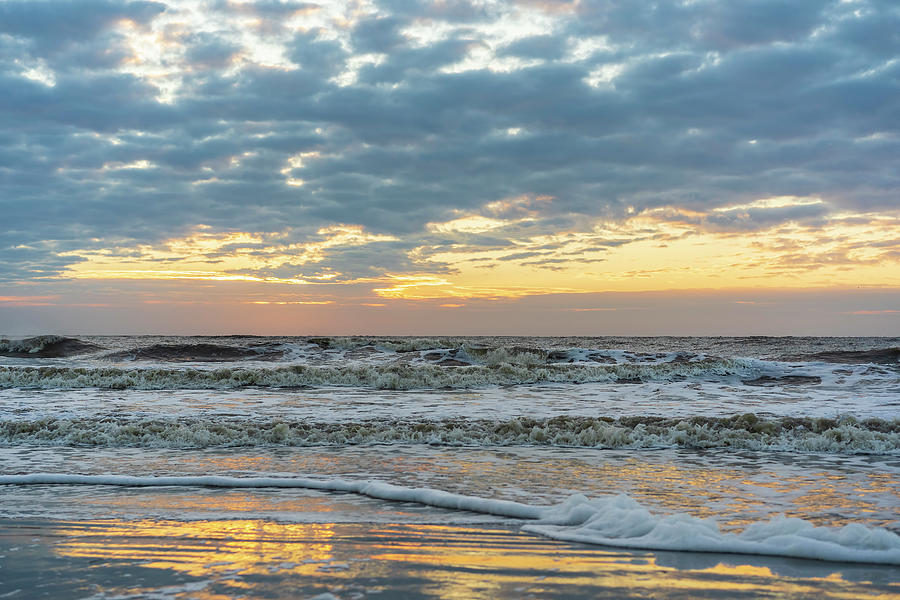 Ocean Waves Rush Toward Sandy Beach Reflecting Glowing Sky At Sunrise
