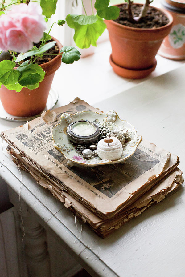 Odds And Ends In Vintage Bowl On Stack Of Old Newspapers Photograph by Camilla Isaksson
