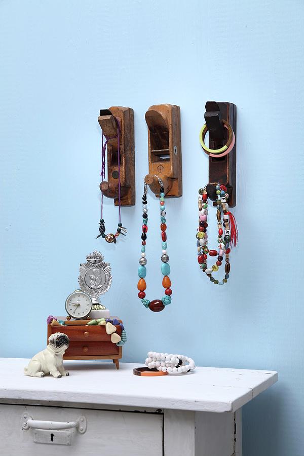 Old Carpenters Planes Used As Decorative Hooks For Necklaces; Ornaments On White-painted Chest Of Drawers Against Blue Wall Photograph by Thordis Rggeberg