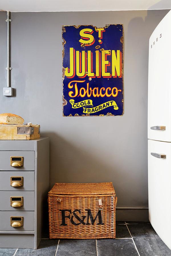 Old Enamel Advertising Sign Above Wicker Trunk Photograph by Rikard Osterlund