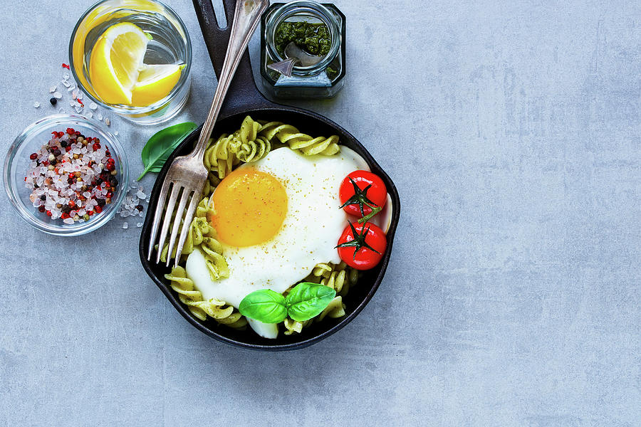 Old Frying Pan Of Tasty Italian Pasta With Pesto Sauce, Fried Egg, Roasted Tomatoes And Basil Photograph by Yuliya Gontar