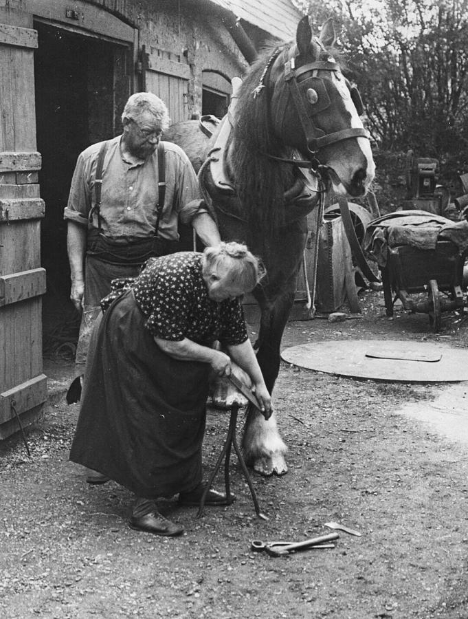 Black And White Photograph - Old Lady Blacksmith by Fox Photos