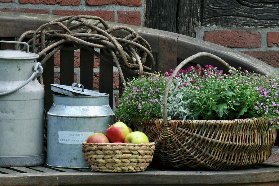 Old Milk Cans, Fruit Basket & Basket Of Flowers On Wooden Bench Photograph by Daniela Behr