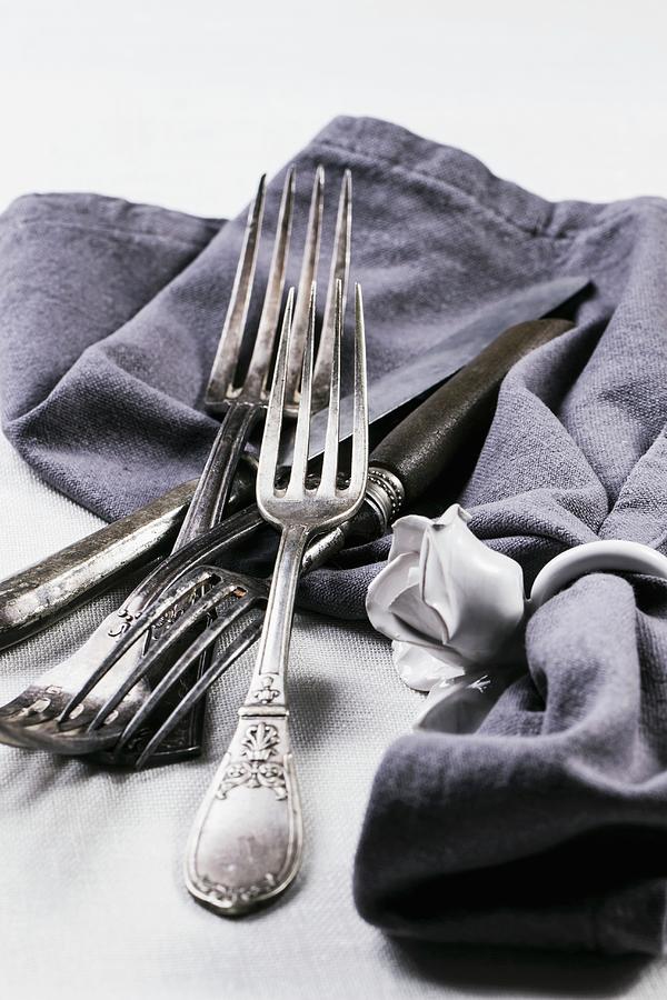 Old Silver Cutlery With A Grey Napkin On A White Table Cloth Photograph by Natasha Breen