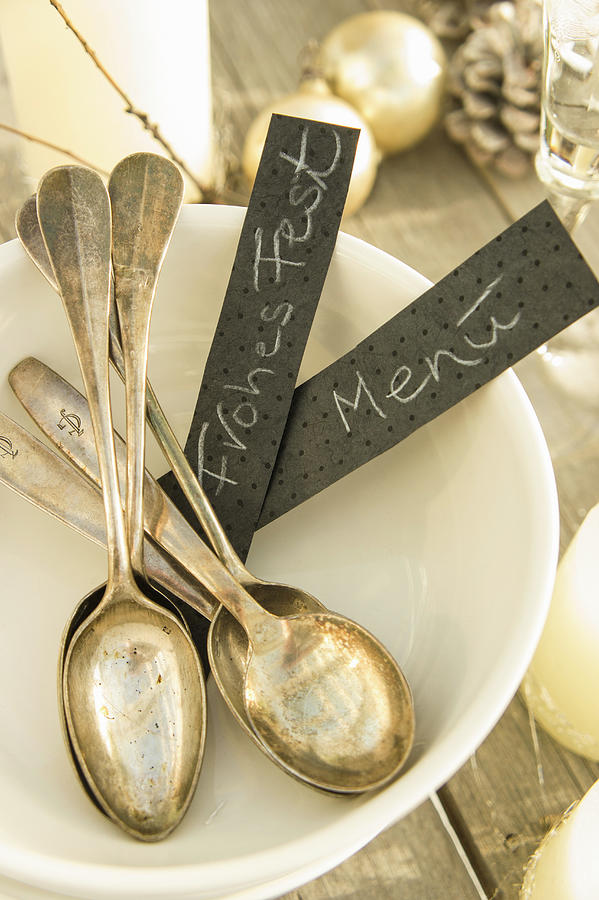 Old Silver Spoons And Labels In A White Bowl On A Christmas Table Photograph by Martina Schindler