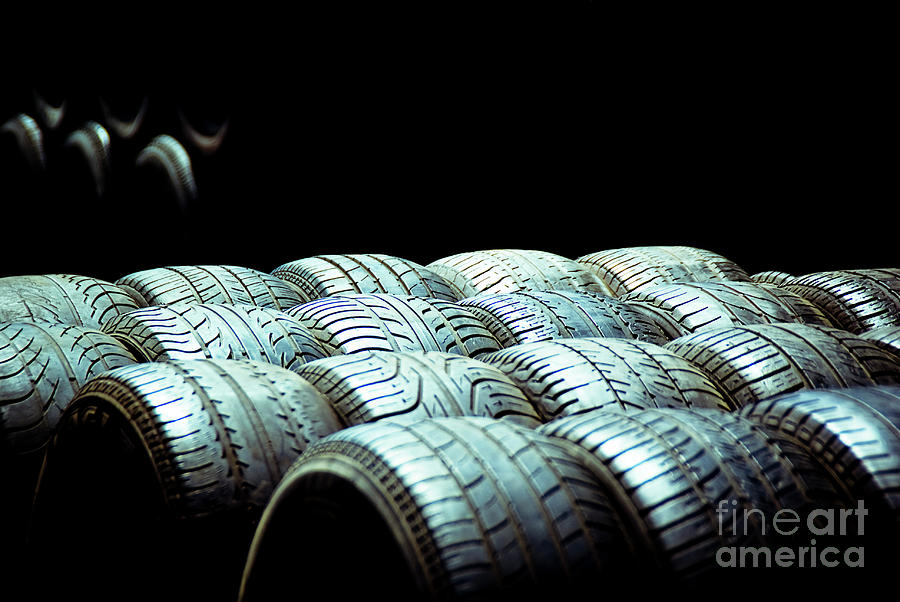 Old tires and racing wheels stacked in the sun Photograph by Joaquin Corbalan