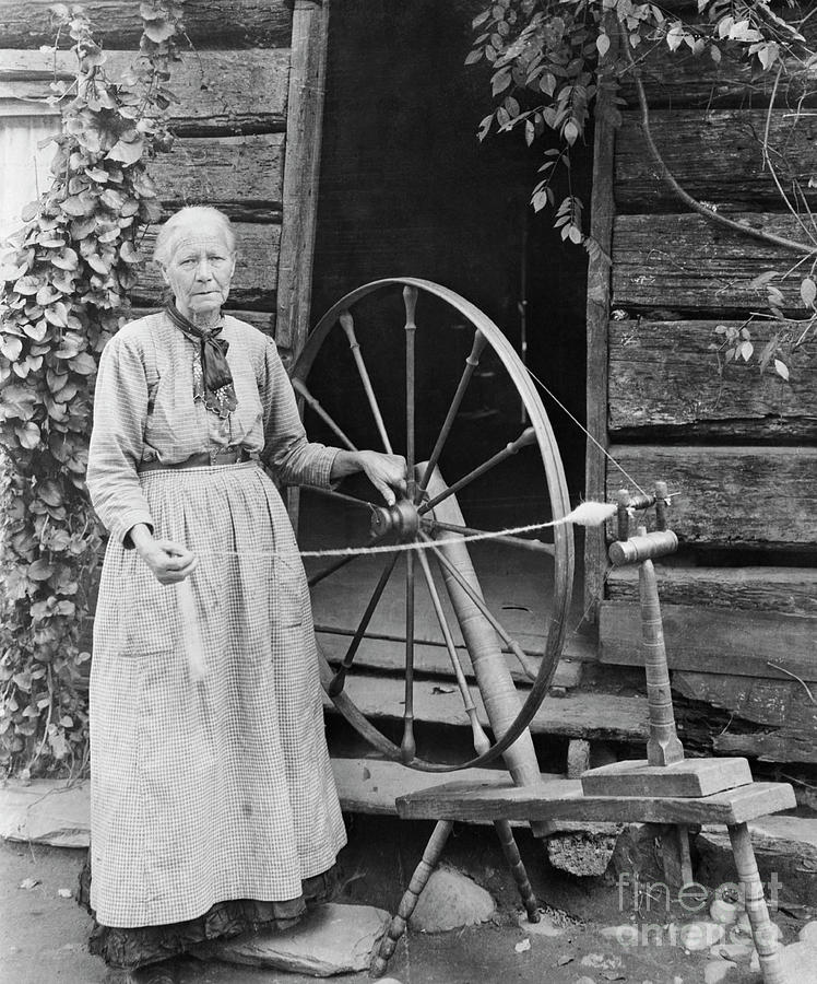 Old Woman At Spinning Wheel Outdoors Photograph by Bettmann