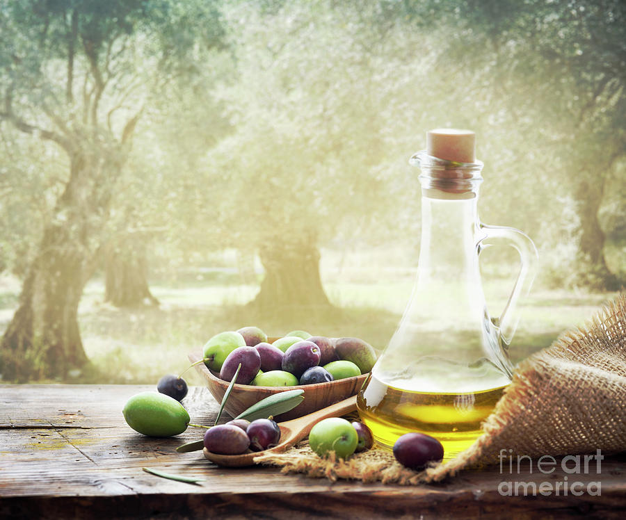 Olives and bottle of olive oil on wooden table in olive garden Photograph by Jelena Jovanovic