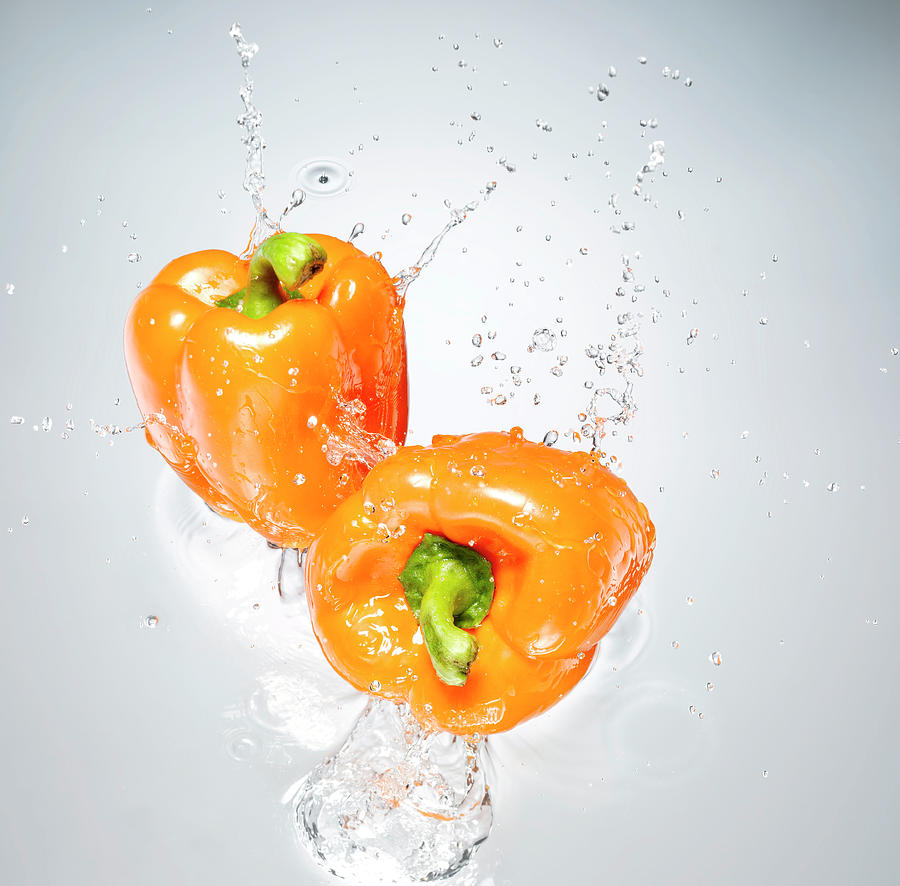 Orange Peppers Splashing In To Water Photograph by Chris Stein