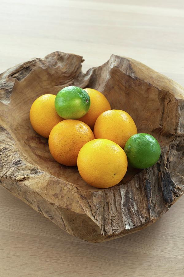 Oranges And Limes In Rustic Wooden Bowl Photograph by Guy Obijn