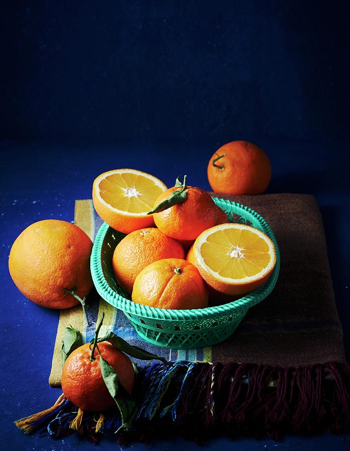 Oranges, Whole And Halved, In A Basket And Next To It Photograph by Hannah Kompanik