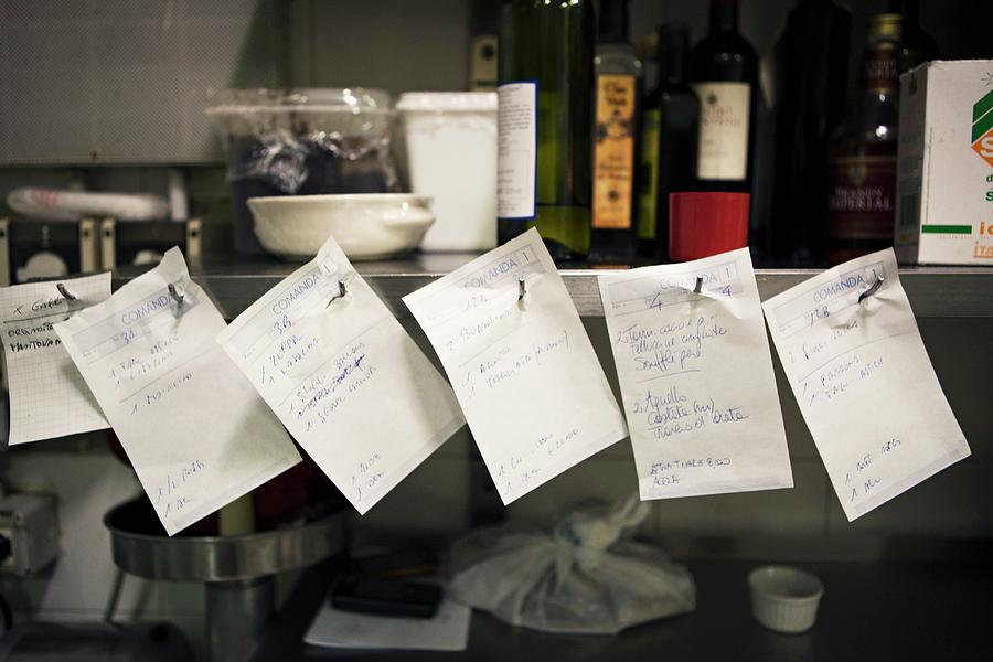 Orders On Pieces Of Paper In A Restaurant Kitchen Photograph by Alex Hinchcliffe