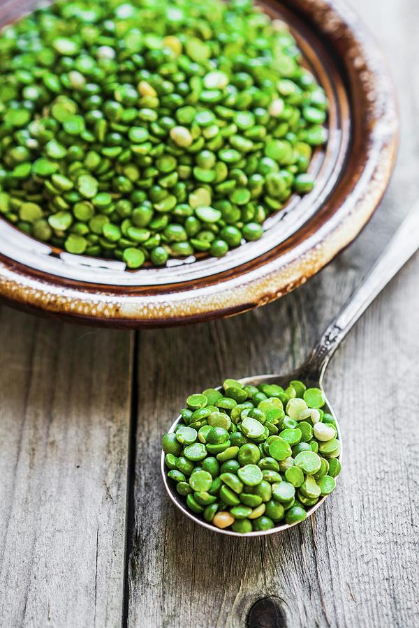 Organic Split Peas On A Spoon And In Bowl On A Wooden Surface Photograph by Alena Haurylik