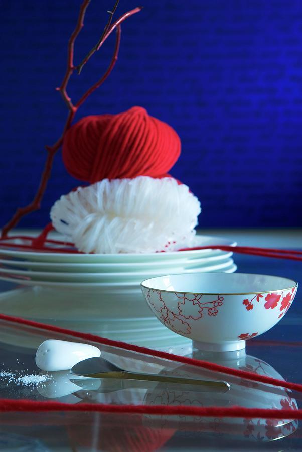 Oriental Table Setting: Bowls Amongst Red Woollen Yarn, Glass Noodles On Stacked Plates And Ball Of Red Yarn Photograph by Matteo Manduzio