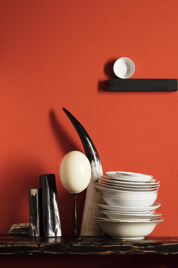 Ostrich Egg, Cows Horn And Porcelain Bowls Against Red Wall Photograph by Roberto Rabe