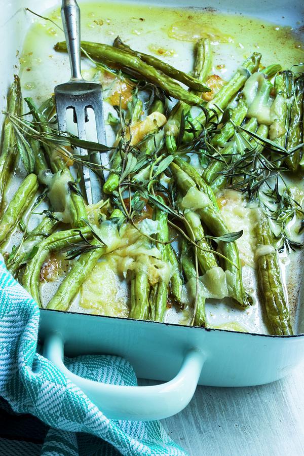 Oven-baked Beans With Herbs And Melted Parmesan Cheese In A Baking Dish With A Fork And A Tea Towel Photograph by Charlotte Von Elm
