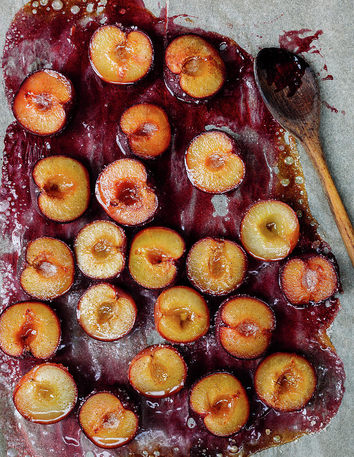 Oven-baked Plums On Baking Paper With A Wooden Spoon Photograph by Anna Haas / Stockfood Studios