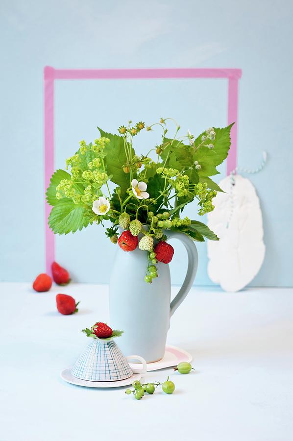 Pale Blue Jug Of Fresh Strawberries, Strawberry Flowers And Ladys Mantle Photograph by Cornelia Weber