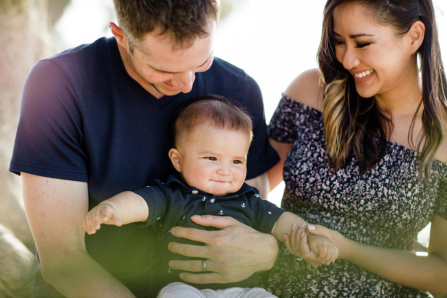 Parents Sitting Under Tree Smiling At Infant Son Photograph by Cavan ...