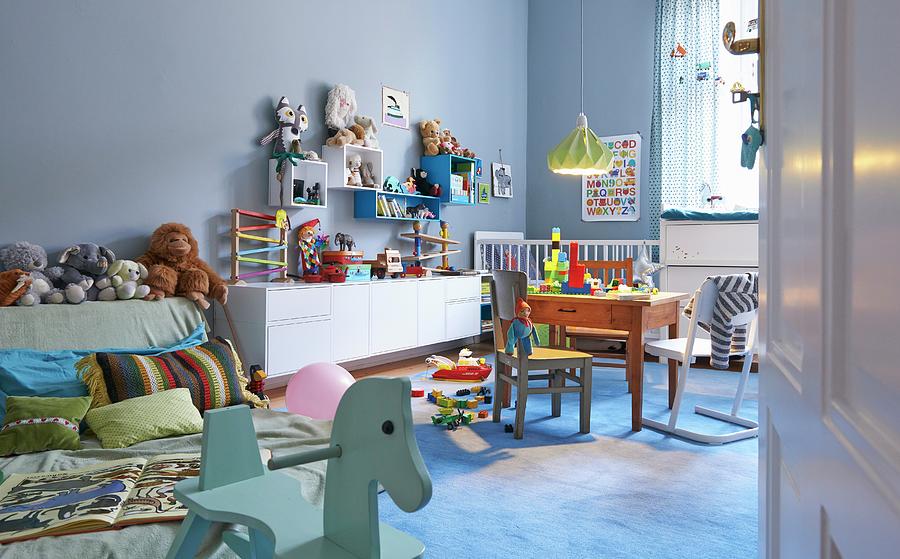Pastel Blue, Spacious Childs Bedroom With Cheerful Wooden Toys And Collection Of Soft Toys Photograph by Stefan Thurmann
