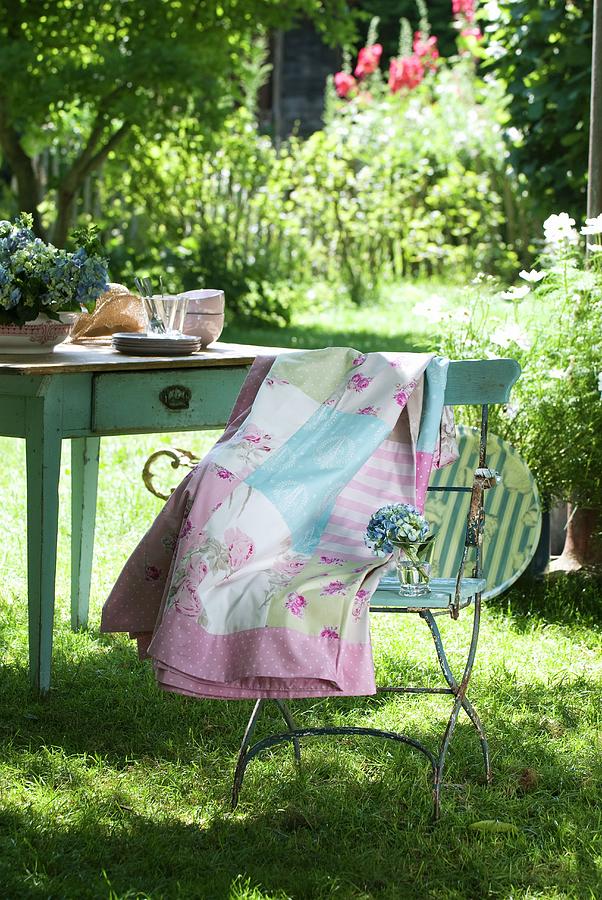Patchwork Blanket With Delicate Patterns Draped Over Garden Chair In Front Of Old Wooden Table In Summer Garden Photograph by Matteo Manduzio