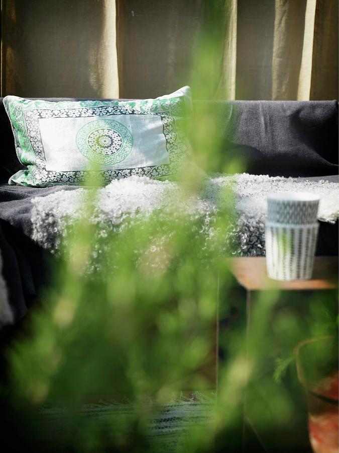 Patterned Cushions On Bench Seen Through Green Leaves Photograph by Peter Carlsson