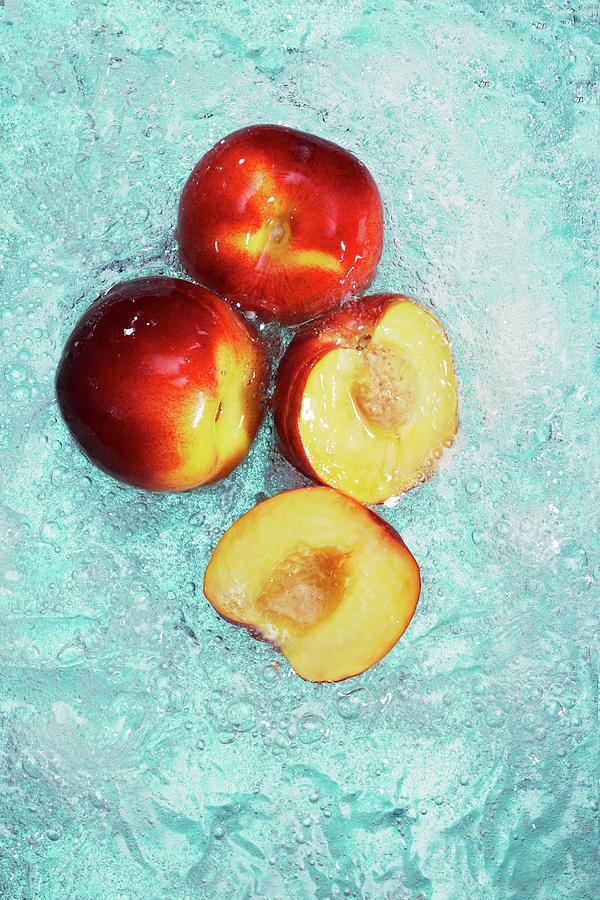 Peaches, Whole And Halved, In Water Photograph by Krger & Gross